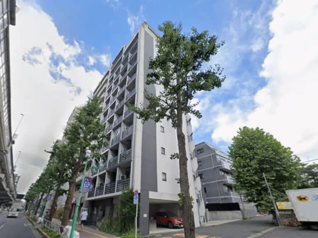 - 現代的なデザインのアパートメントビル、周囲に緑豊かな木々があり、晴れた空の下に立つ景観
