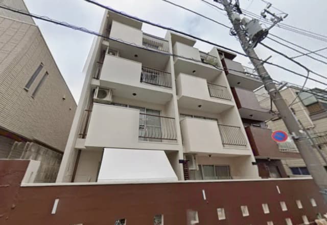 - シンプルでモダンなデザインのマンション外観、バルコニーと窓があり、周囲に電柱が立つ街並み