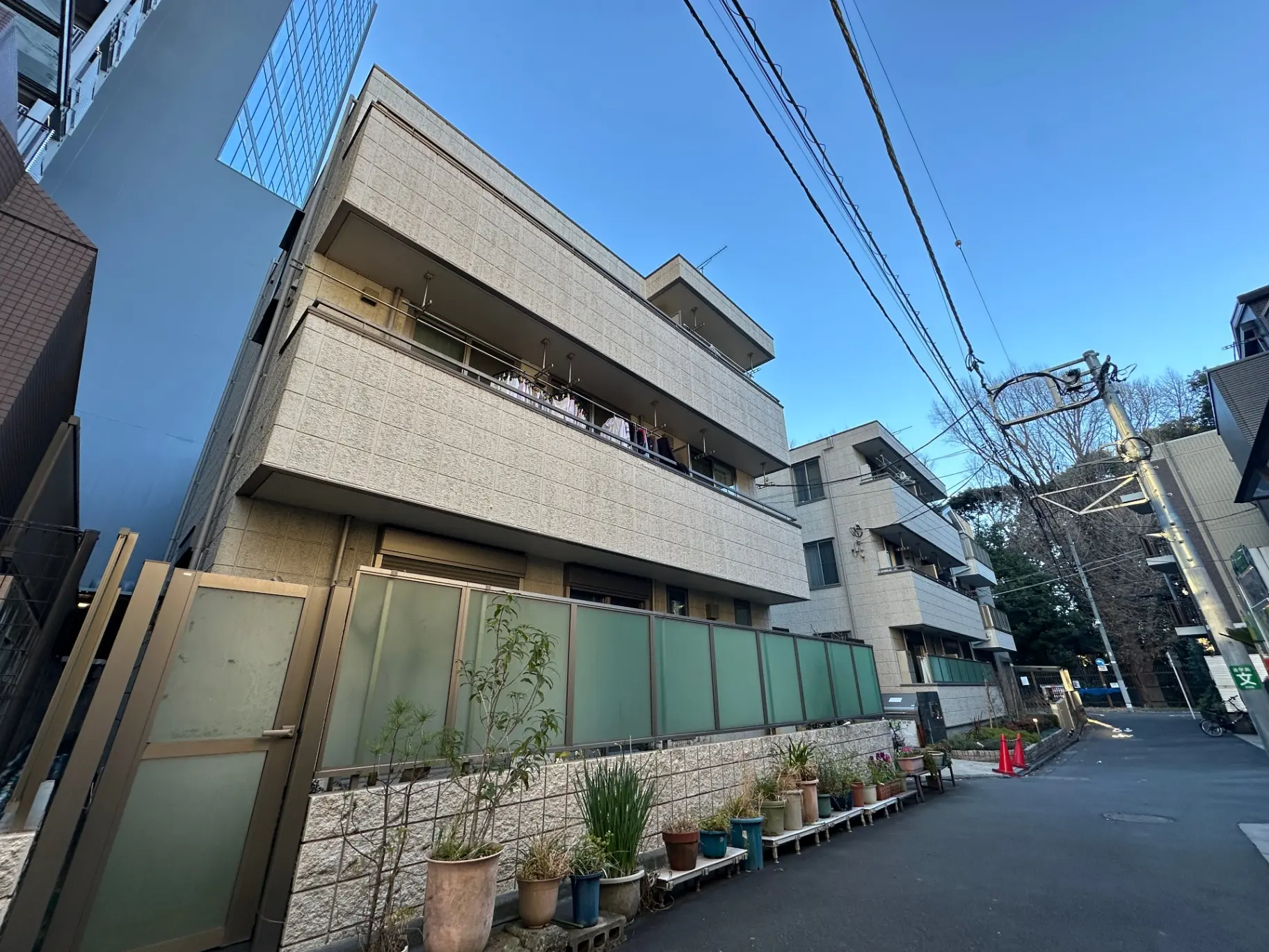 現代的な建築スタイルの住宅街、青空の下のアパートと植木鉢が並ぶ歩道