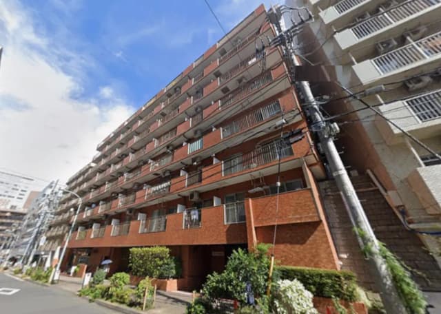 - 赤レンガの外観を持つマンション、 balconiesと窓が並び、周囲に緑が配置された都市の風景