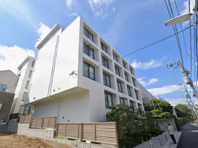 - モダンなデザインの集合住宅、白い外壁と大きな窓、周囲に緑が取り入れられた景観