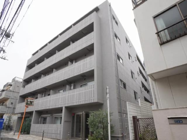 - モダンな外観のダイニングビル、グレーのファサードとバルコニーが特徴、周囲には別の建物や電線が見える街並み