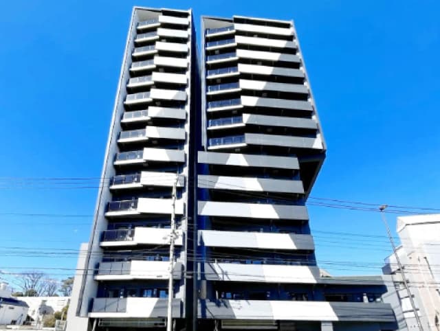 - 青空の下にそびえる現代的なデザインの高層マンション、バルコニー付きでエレガントな外観