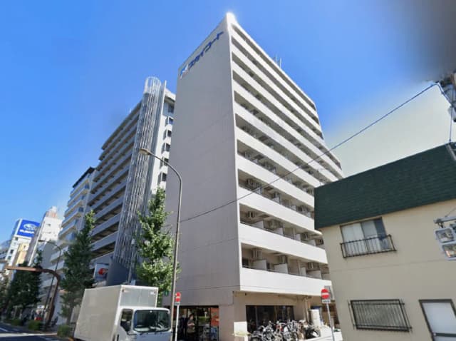 - 都心にあるモダンなマンションの外観、青空を背景にした6階建ての建物と周囲の緑が特徴的な景観