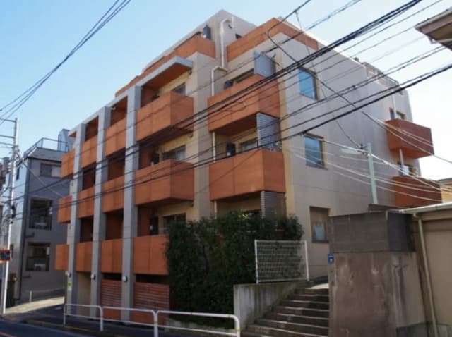 - オレンジのバルコニーが特徴的な現代的な集合住宅、周囲には電線が張り巡らされている街並み