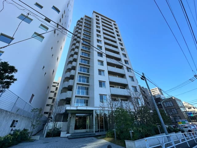 現代的なマンションの外観、エントランスにガラスドア、都市の建築と青空