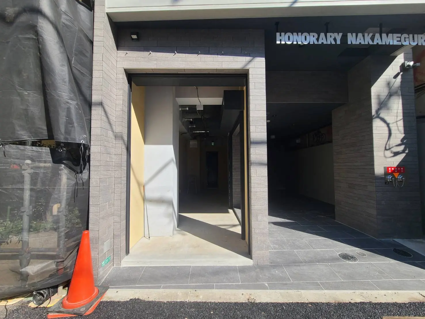 店舗入口の外観、日差しが明るい歩道、モダンな建築スタイル