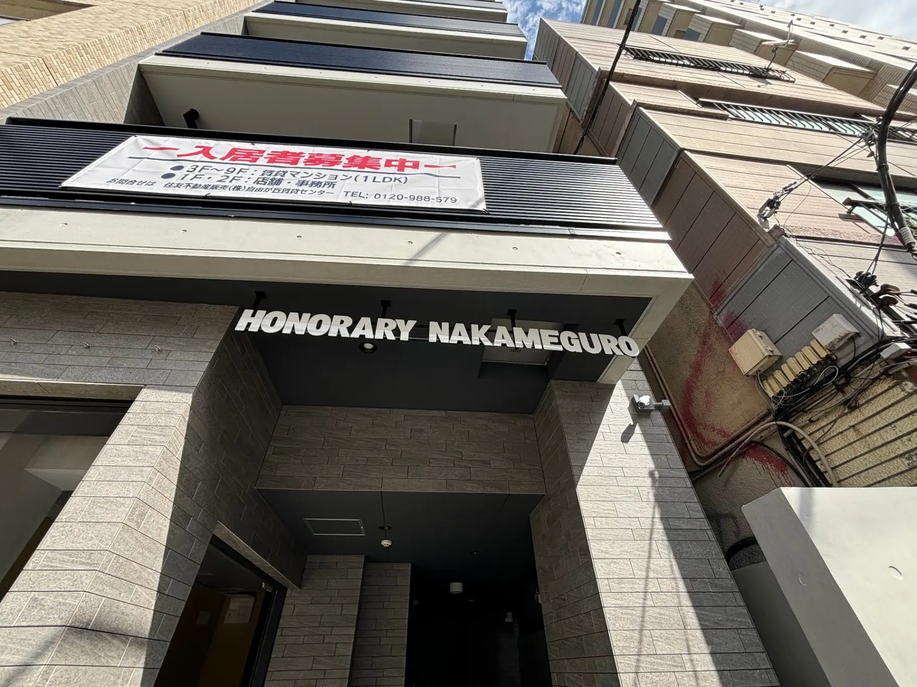 中目黒にあるモダンな外観のマンションエントランス、日差しが差し込む都市の住居