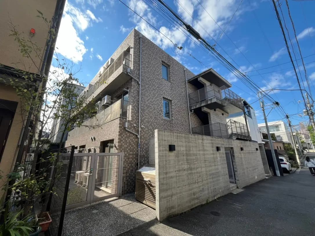 現代的な外観のアパートビル、青空と白い雲、周囲に電線がある都市風景