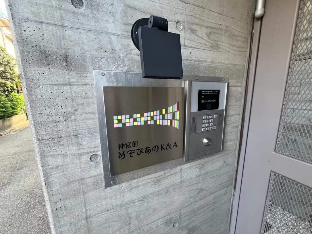 コンクリートの壁に取り付けられたインターホンと表札、カラフルなタイルデザインが特徴