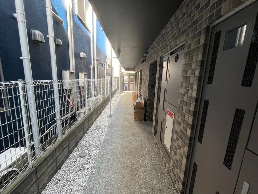 狭い都市の路地、アパートの外観、石畳と配管が見える通路