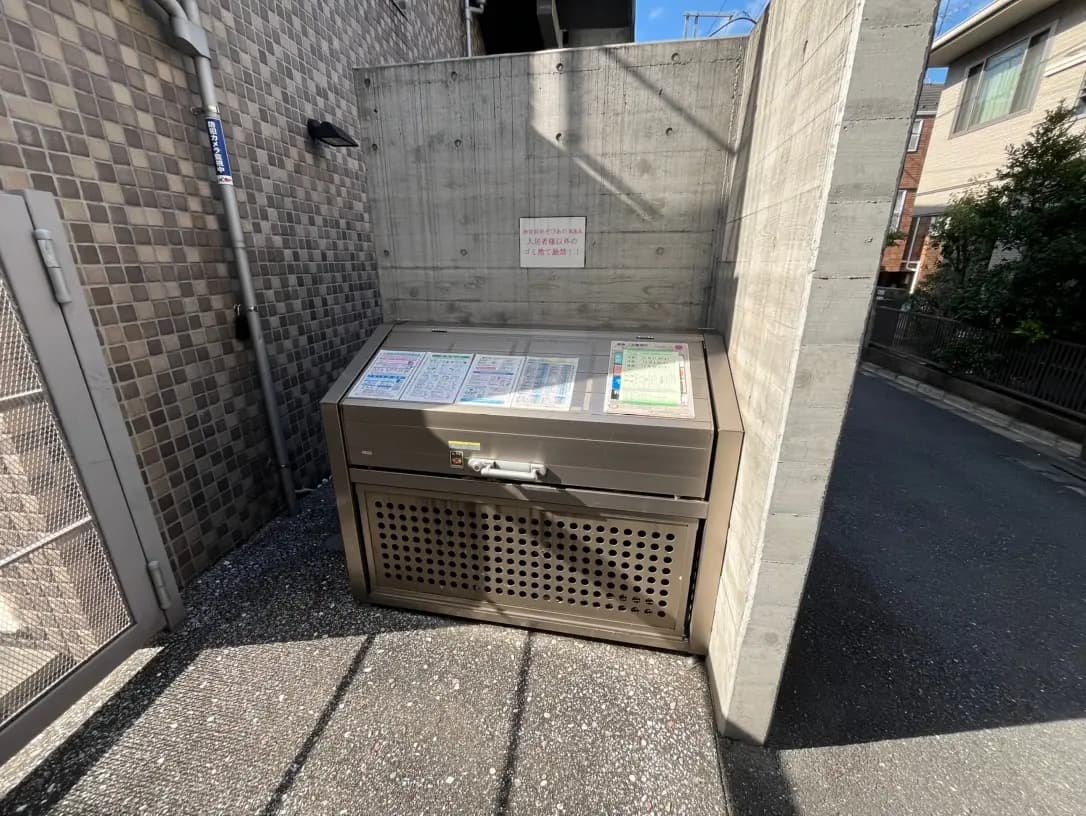 日本の住宅街に設置された屋外ゴミ収集ボックス、コンクリートの壁とタイル張りの地面