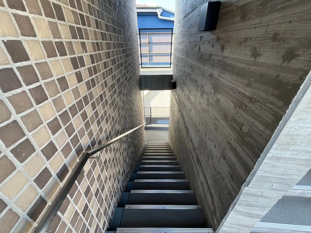 モダンな建築の階段、タイル張りの壁と木目調の壁面、自然光の入る空間