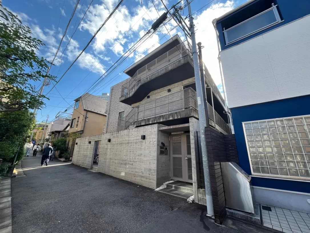 日本の住宅街にある現代的なアパート建物、晴れた日の青空、散歩する人々