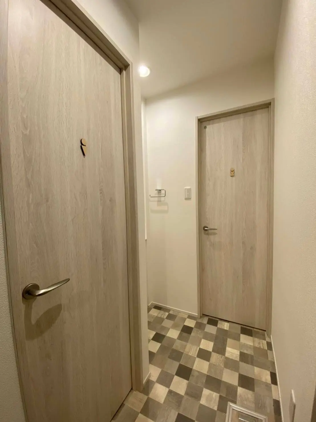 シンプルなデザインの玄関ホール、木目調のドアとチェック柄のフローリング