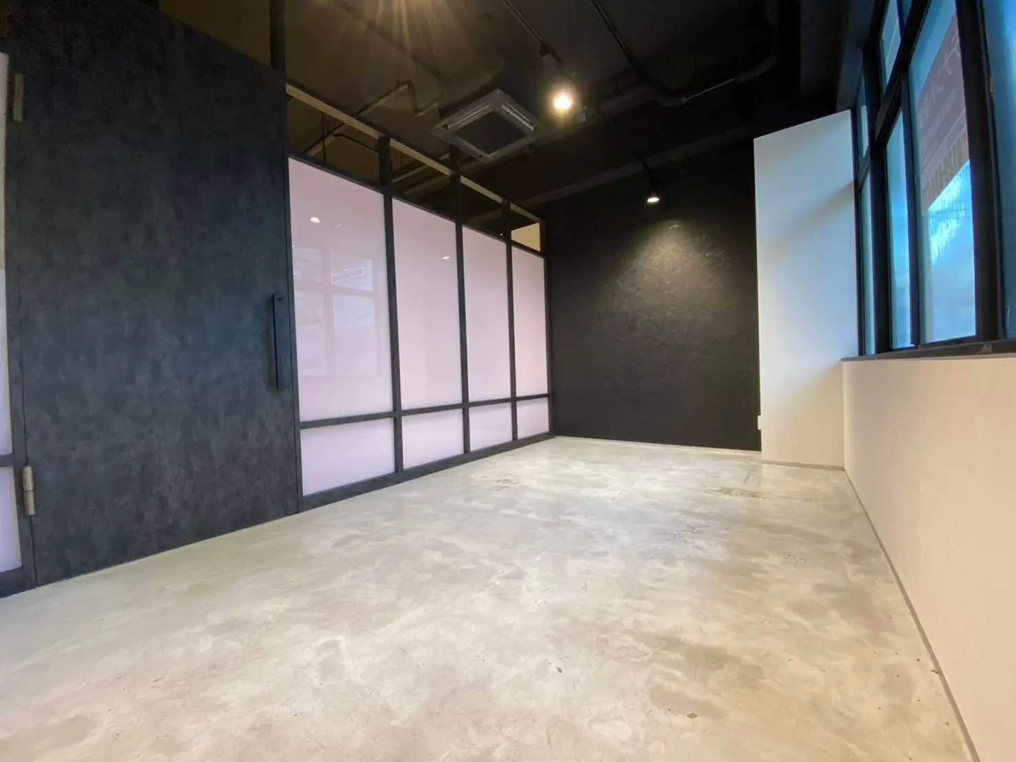 モダンなオフィス空間、グレーのフローリング、大きな窓と明るい照明のインテリア