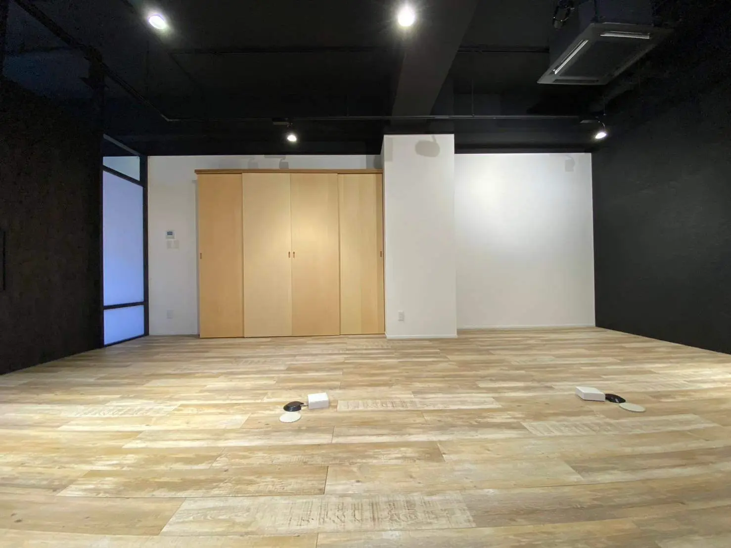 モダンなデザインの木製フローリング、黒い天井と白い壁のコントラストが映える空間