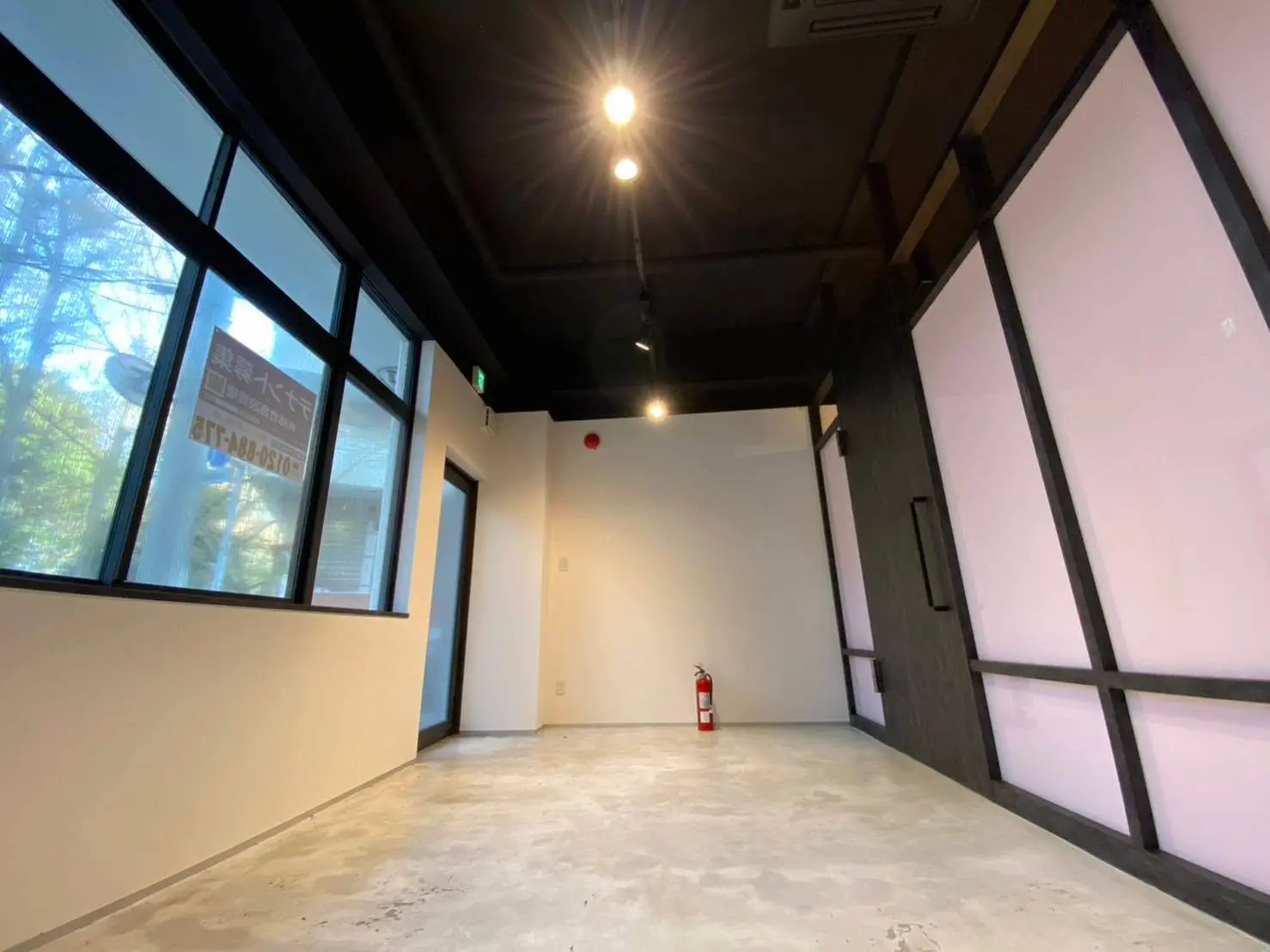広々とした空間の店舗やオフィス、大きな窓とコンクリートの床、シンプルでモダンなインテリア