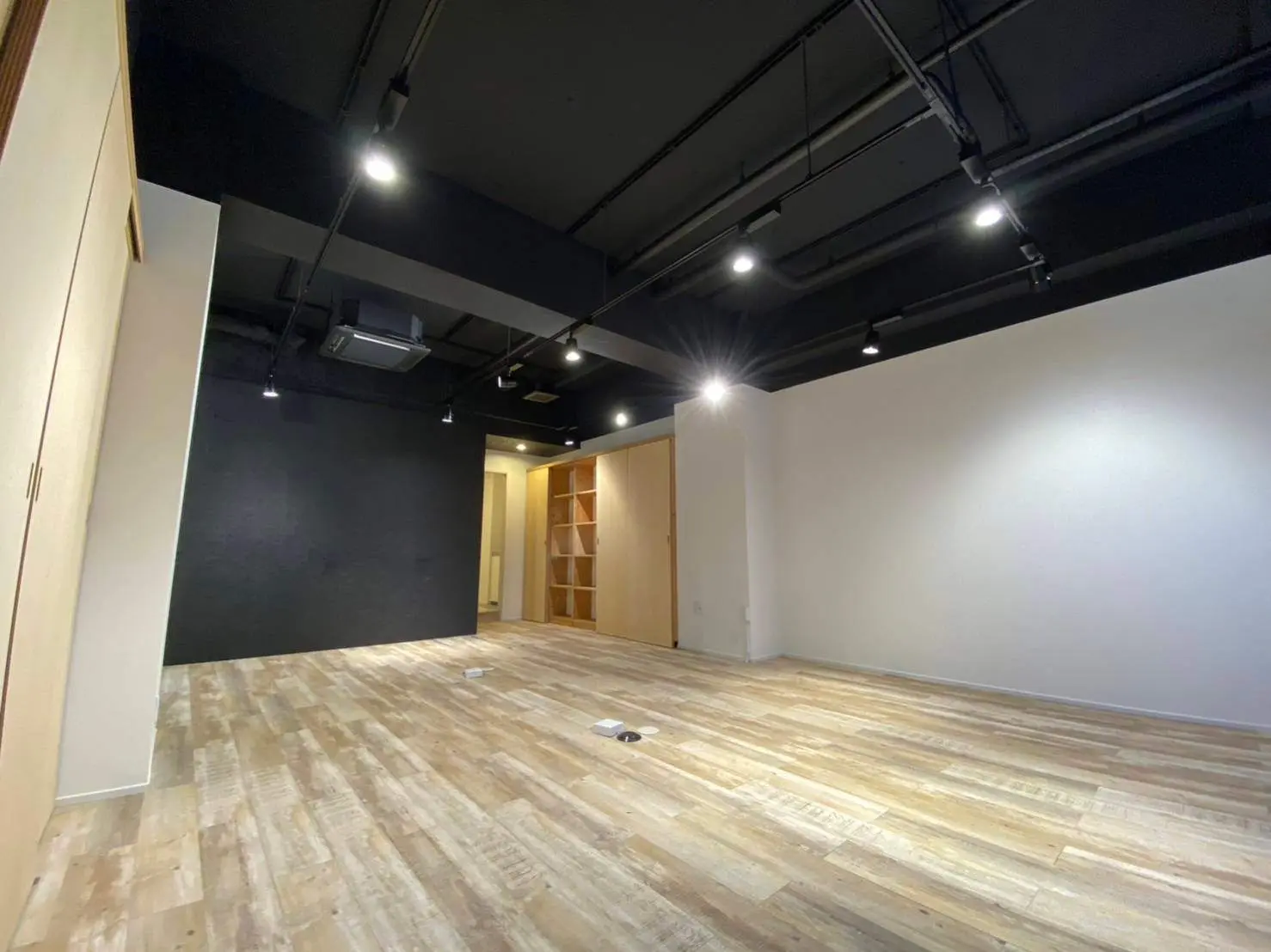 広々とした現代的な空きスペース、木製フローリングと黒い天井の施工途中のオフィスまたは店舗のインテリア