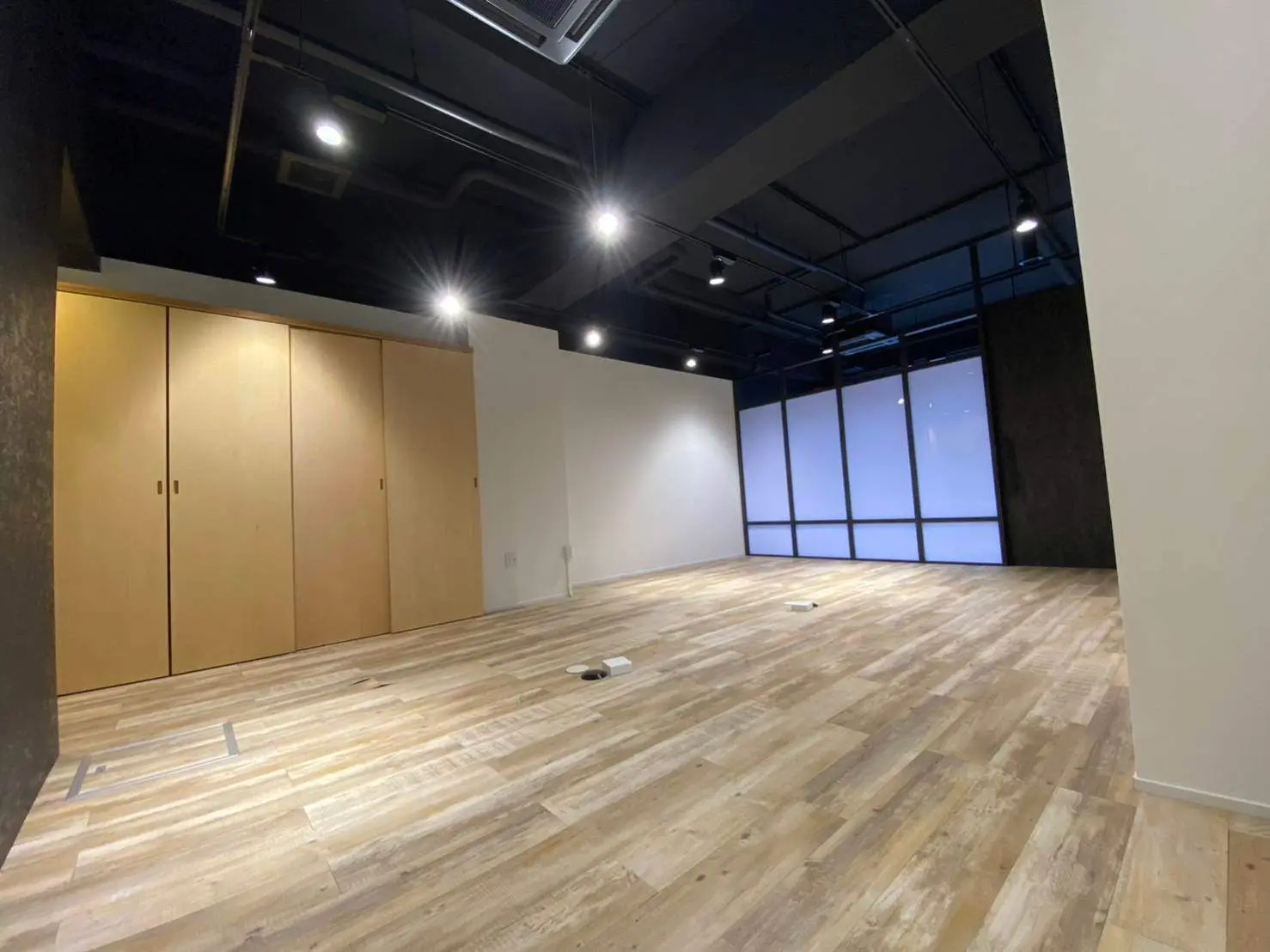 空間広々としたオフィス空間、木製のフローリングと大きなガラス窓のインテリア設計