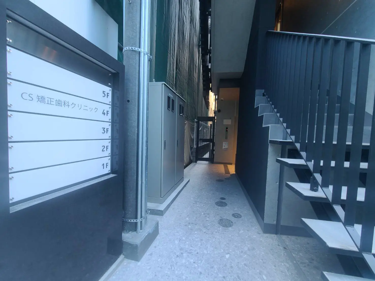 - 鉄筋コンクリート製のモダンなエントランス、階段と壁に設置された案内板がある通路の画像
