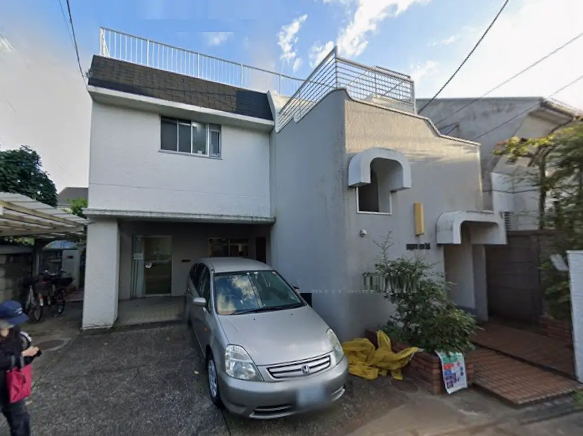 - シンプルで現代的な外観の住宅、駐車場に停まったシルバーの車、青空の下に建つ家の紹介