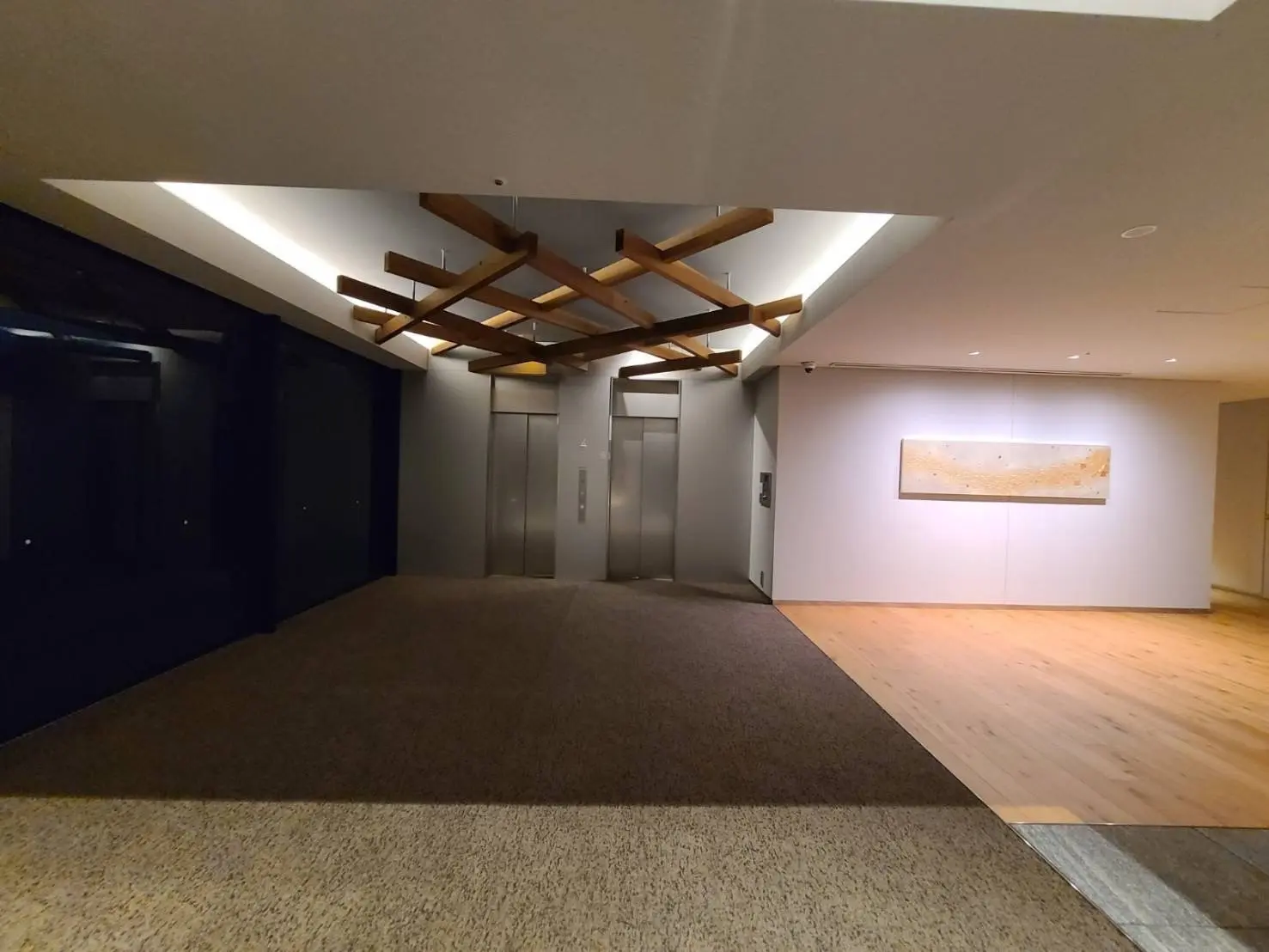 ラグジュアリーなエントランスホール、目を引く木製の天井デザインとモダンなアートが飾られた壁