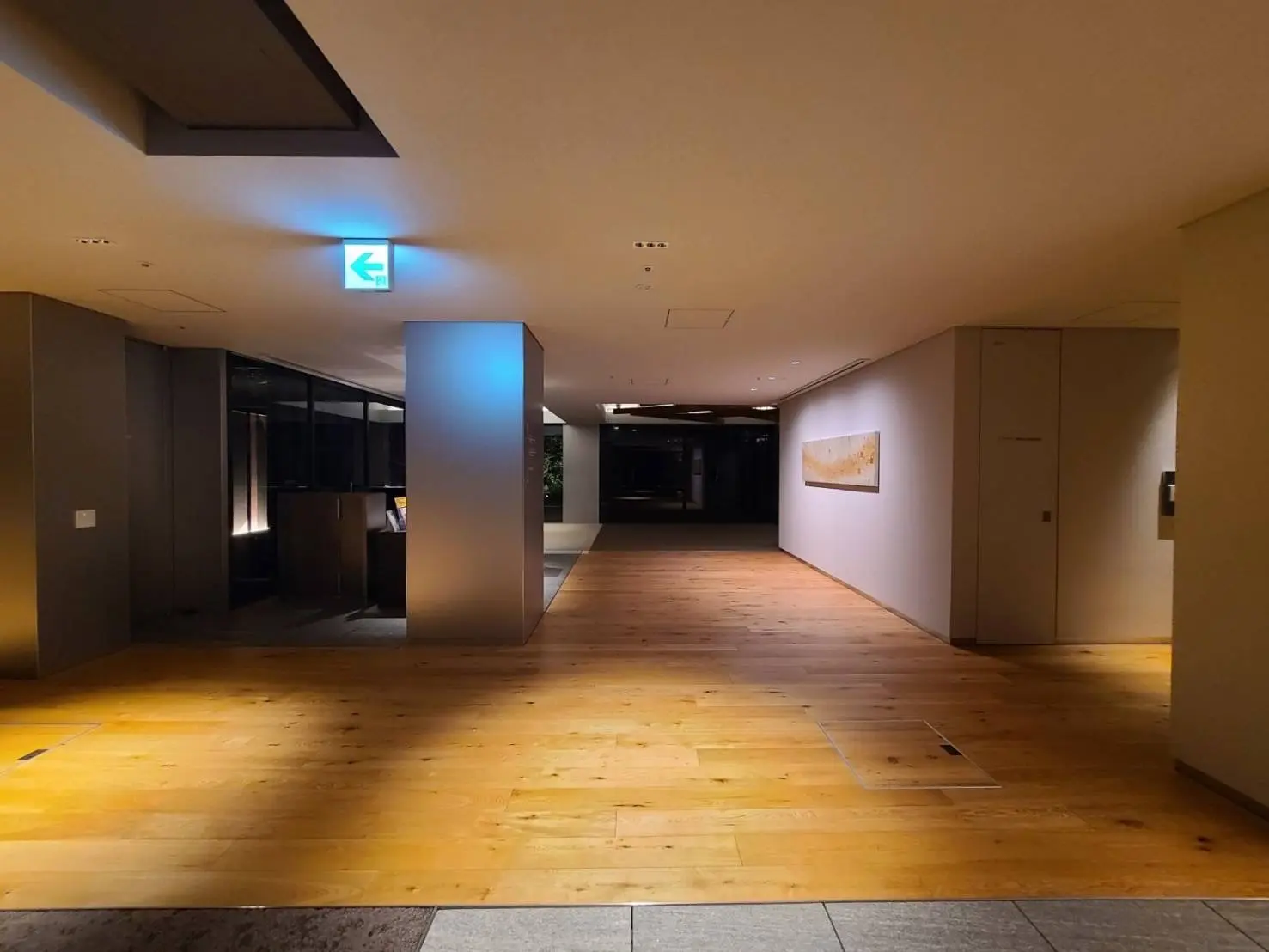 モダンな木製フローリングのオフィスビルの内廊下、照明が施されたシンプルなデザインの空間