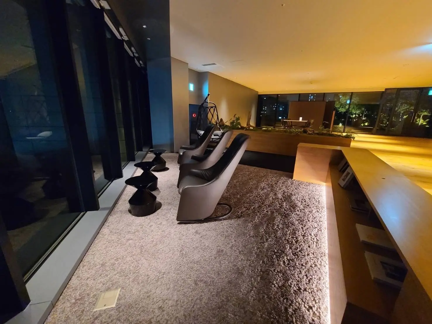高級感のあるモダンなラウンジスペース、照明付きの木製カウンター、快適なリクライニングチェアと柔らかいカーペット