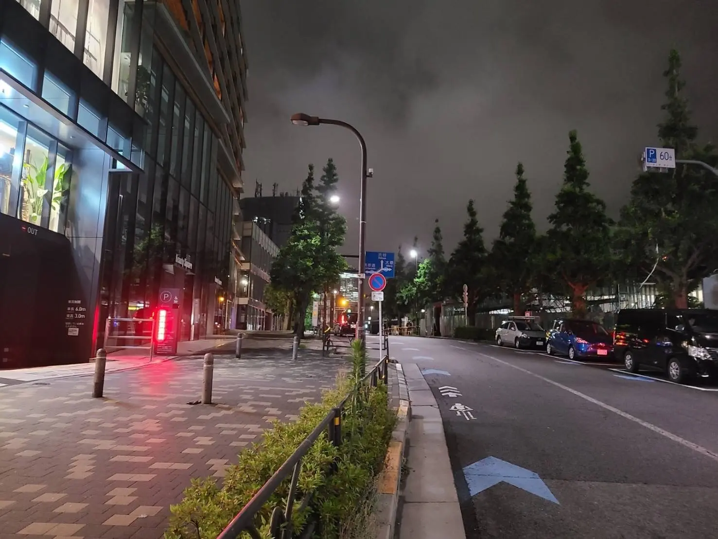 夜の街並み、建物の外観、街路樹と駐車場、自転車レーンが描かれた歩道