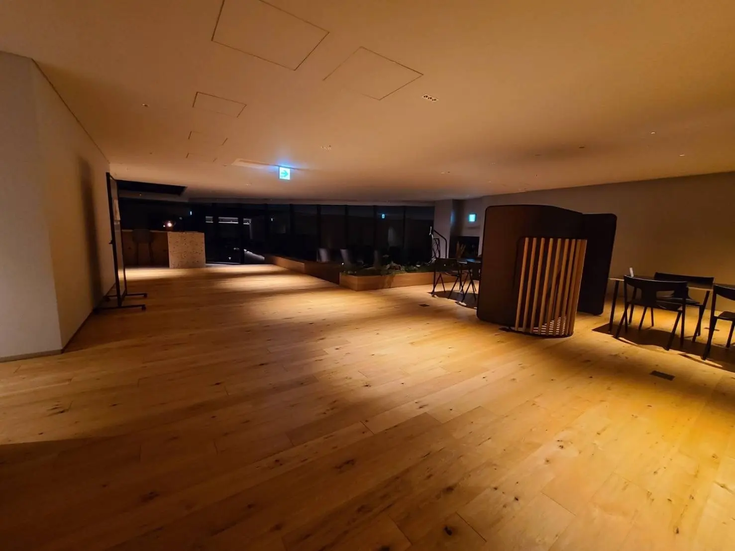 モダンな雰囲気の木製フローリングの床、暖かい照明とスタイリッシュな家具が配置された広々とした空間