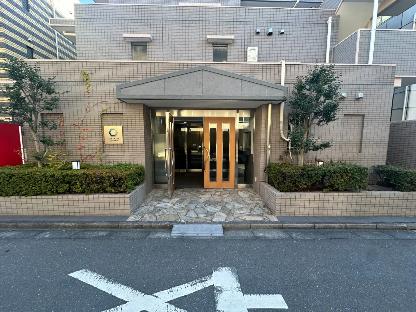 外観がモダンなオフィスビルの入り口、石畳のアプローチと緑豊かな植栽