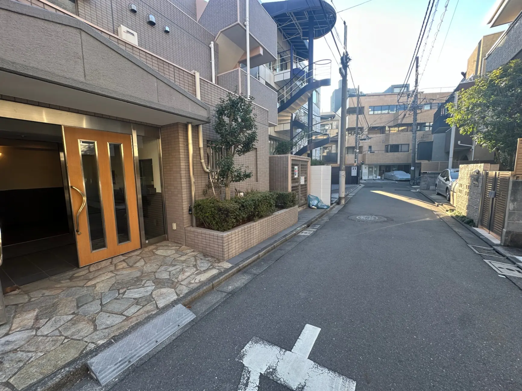 日本の都市部にあるマンションのエントランス、石畳と植栽がある閑静な住宅街