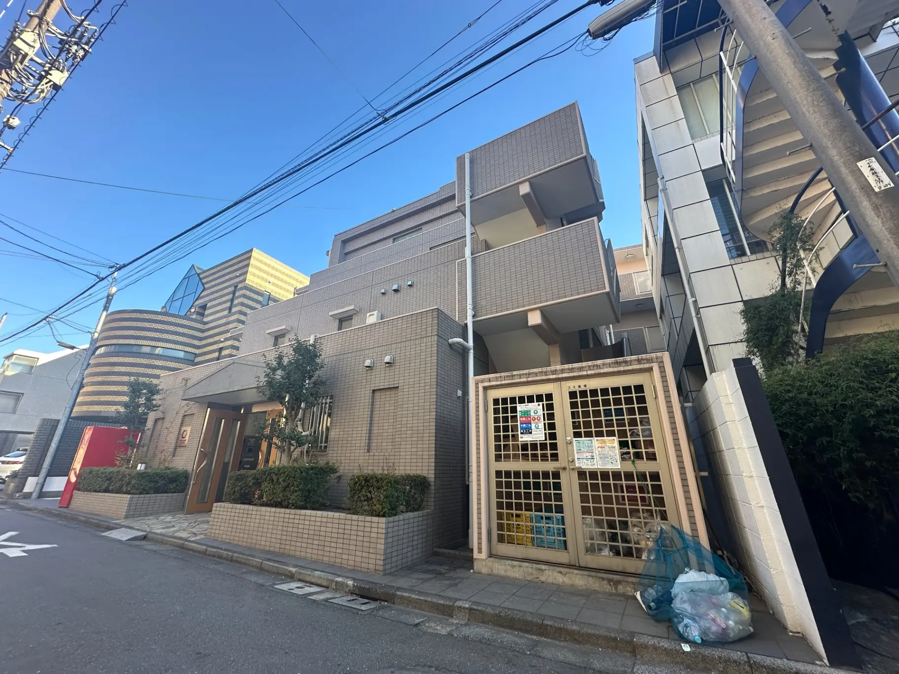都会の静かな住宅街に建つモダンな建築物、青空と電線が交差する景色
