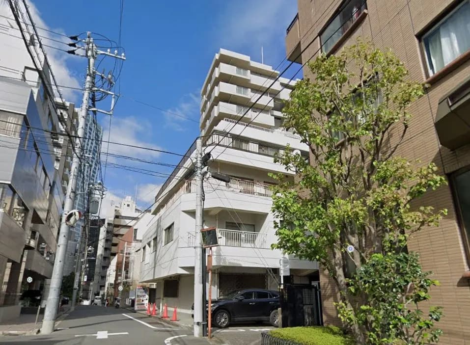 日本の都市部の住宅街、電柱と電線が林立し、マンションと商業ビルが混在する風景