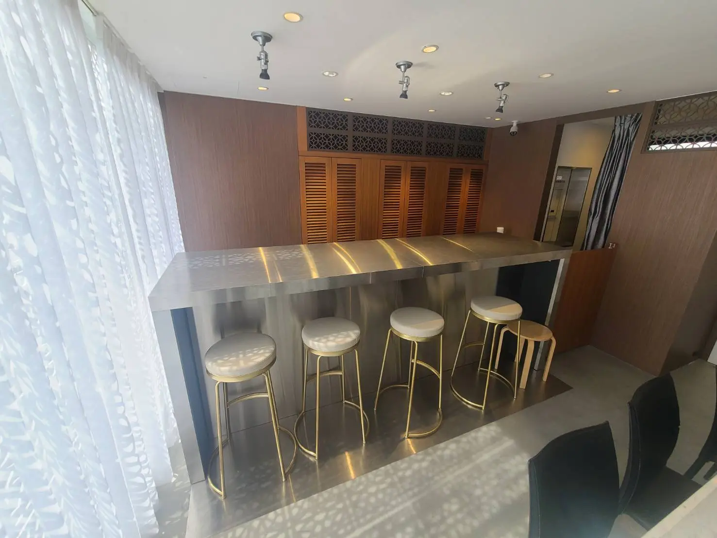 シックなモダンキッチンバーカウンター、ゴールドのアクセントとバースツール、洗練されたインテリアデザイン