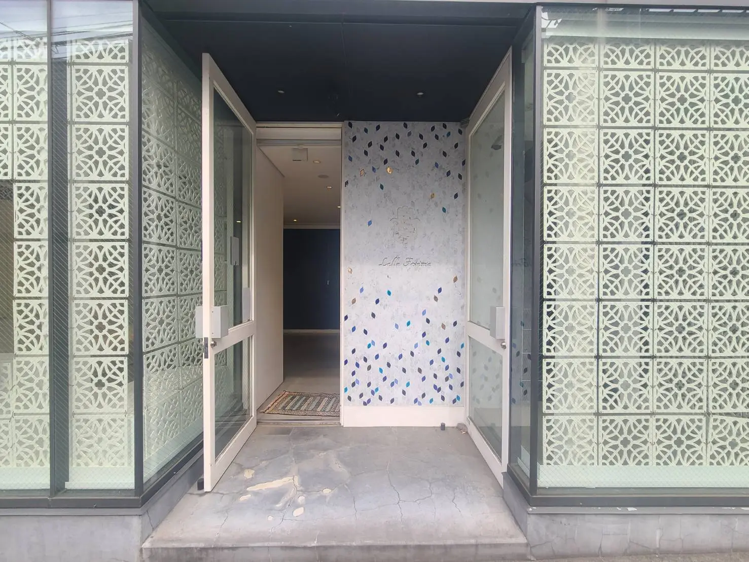 モダンなエントランスデザイン、オリジナルのガラス装飾が施された開き戸、洗練された外観のビル入口