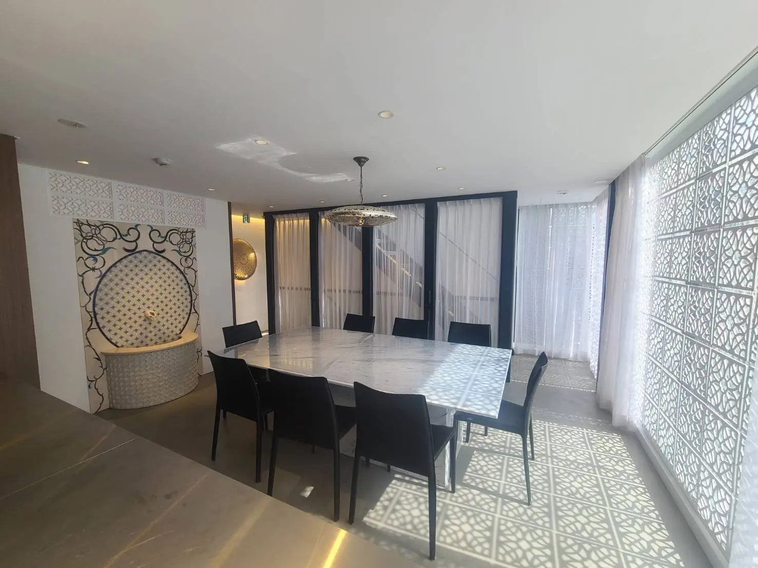 現代的なデザインのダイニングルーム、装飾的なパーティション、白いカーテンと天井の照明が特徴的なインテリア