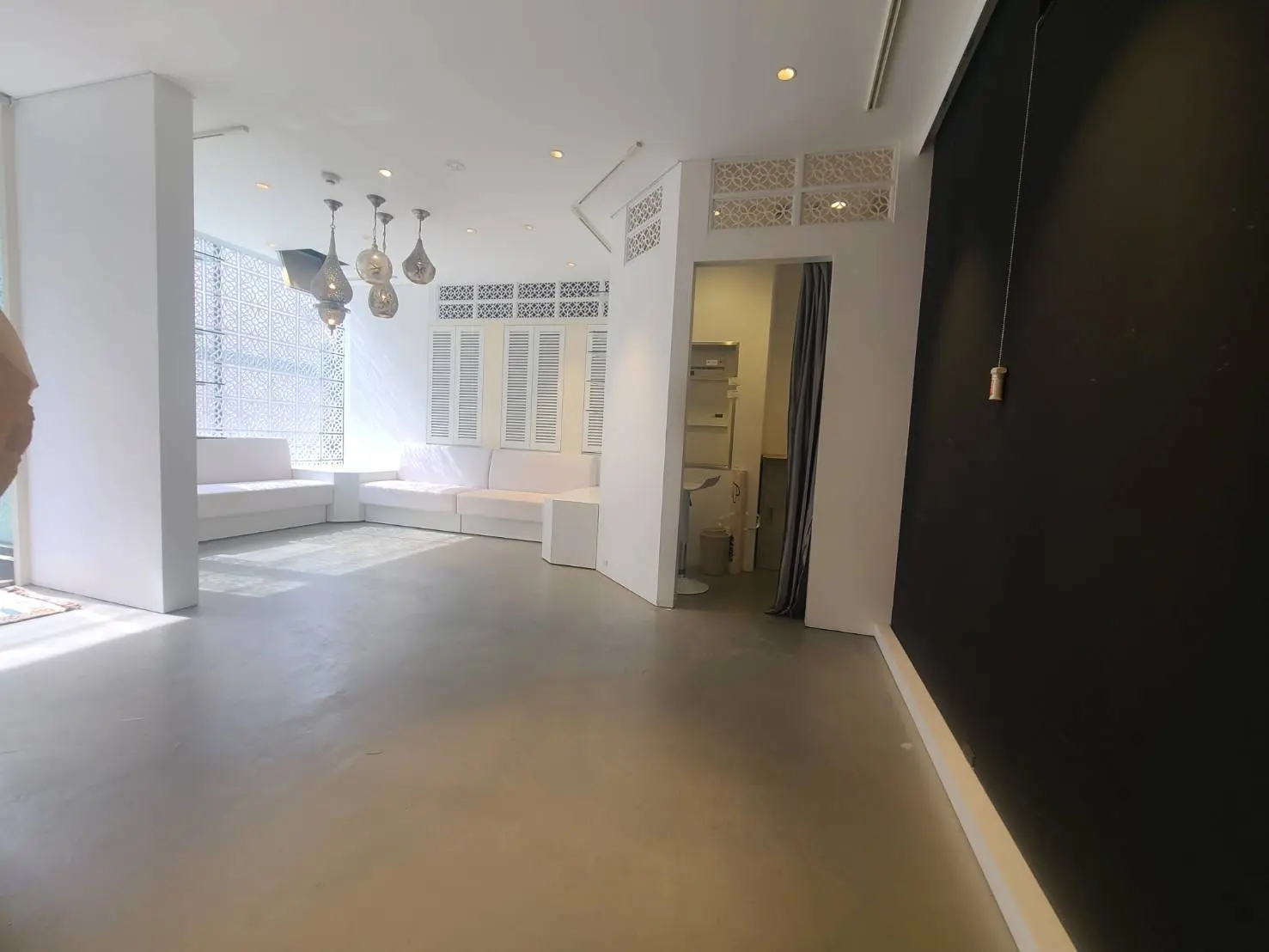 ミニマリストデザインのリビングルーム、白いソファとジオメトリックパターンの壁、モダンな照明器具と床から天井までの窓