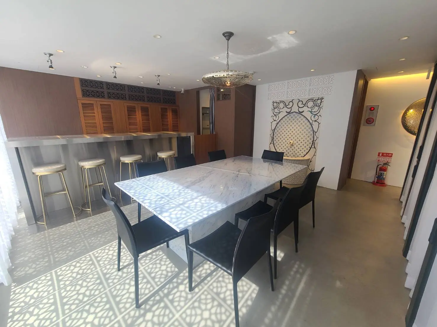 モダンなダイニングエリア、大理石のテーブルと黒い椅子、バーカウンターとスツール、装飾照明とユニークな床のデザイン