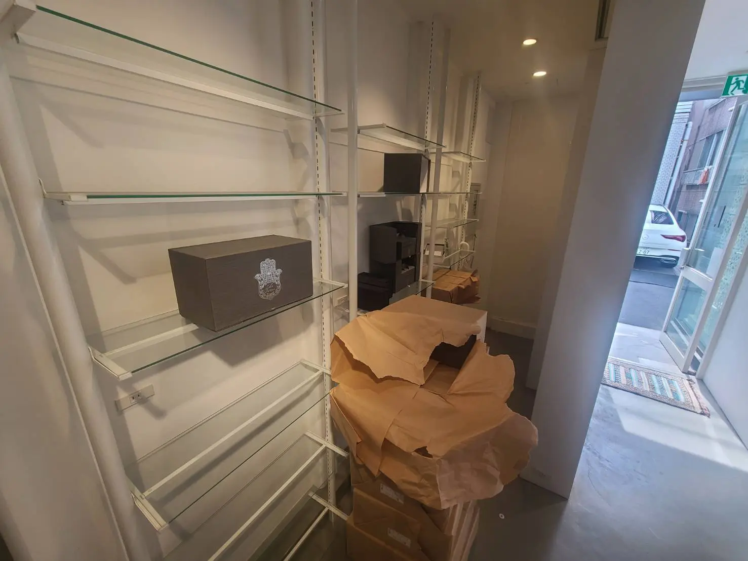 未完成の店舗の内装、ガラス棚に段ボールが積まれている様子