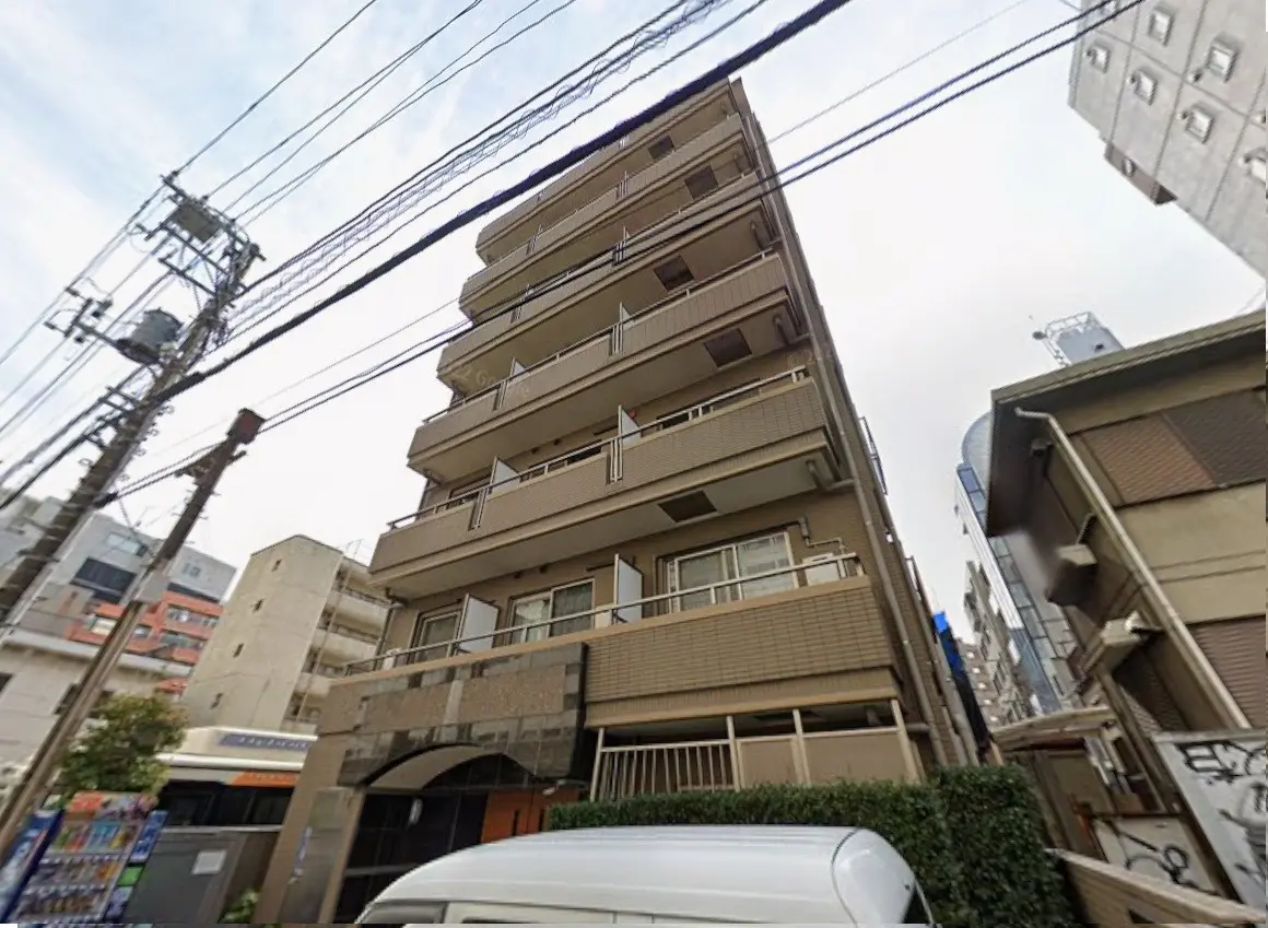 都市の景観、複数のバルコニーがある多階建てのアパートビル、電柱と配電線が見える