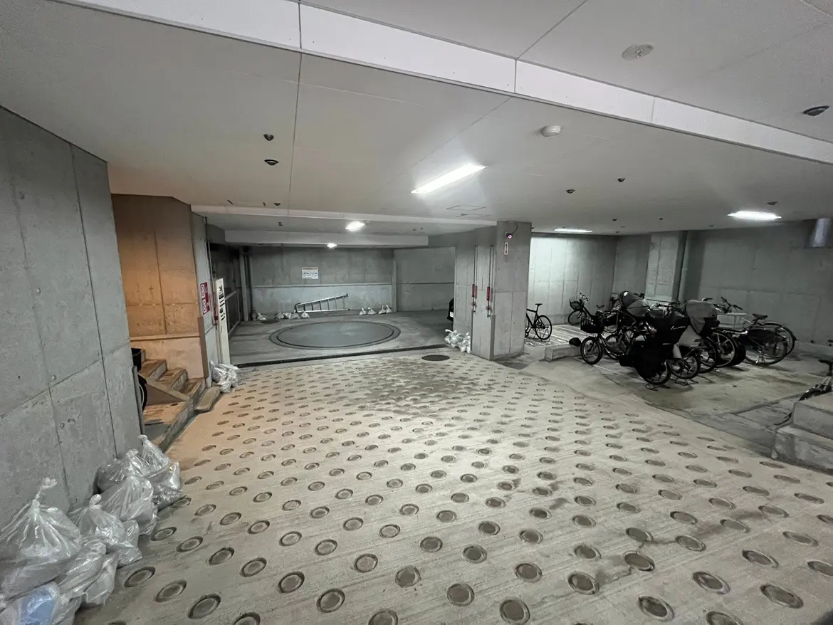 地下駐輪場の様子、自転車が整然と駐輪されている光景、回転式エントリーゲートとコンクリートの壁