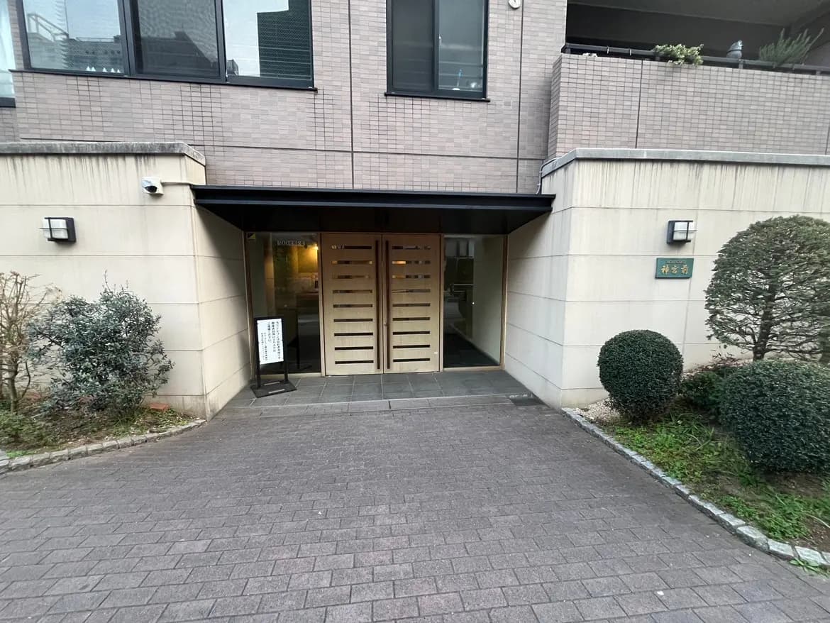 現代的なマンションの入り口デザイン、緑の低木と共に落ち着いた色合いの外観