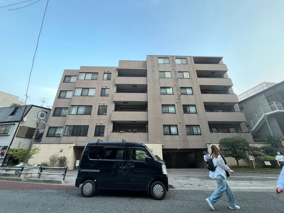 現代的なマンションの外観と前を歩く人々、クリアな青空