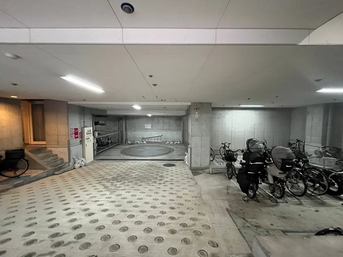建物内の自転車駐輪場、円形の回転式駐輪スペースと階段、駐輪されている自転車が多数あり、清潔で整頓された空間