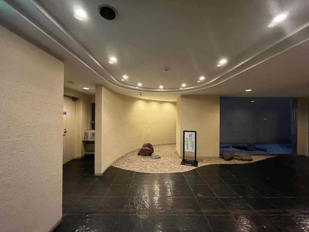 モダンな建物のエントランスホール、柔らかい照明、黒い床タイル、ゆったりとしたスペース