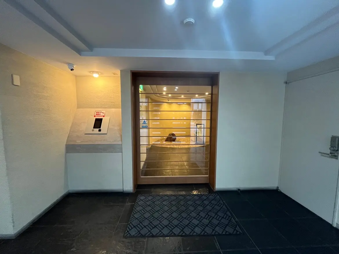 玄関エリア、セキュリティシステムが設置されたモダンなオフィス入り口、照明とクリーンなデザイン