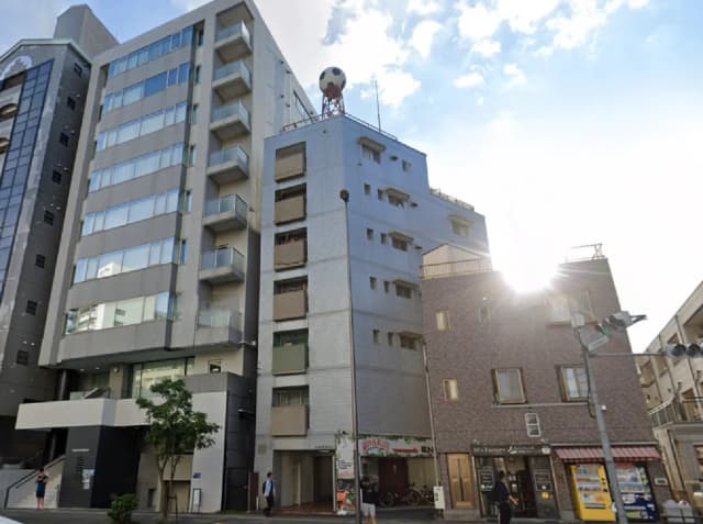 - 都市型ビルが立ち並ぶ街の風景、光が差し込む中にモダンな建物とレトロな店舗が調和した印象