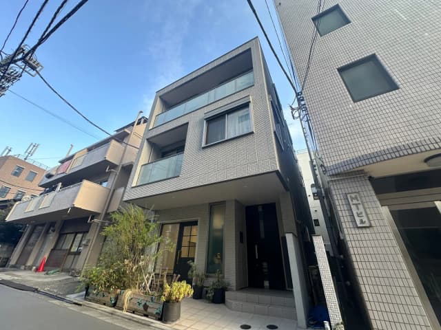 都市型のモダンな外観のアパート、洗濯物が干されているバルコニー、植栽が配されたエントランス